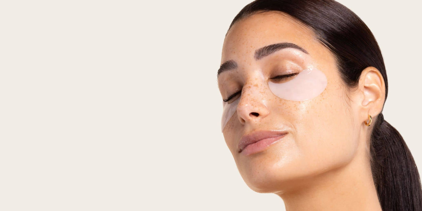 woman wearing 5 minute under eye patches on a light tan background