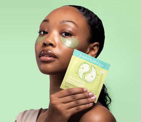 woman wearing cool crush under-eye patches to depuff on a green background