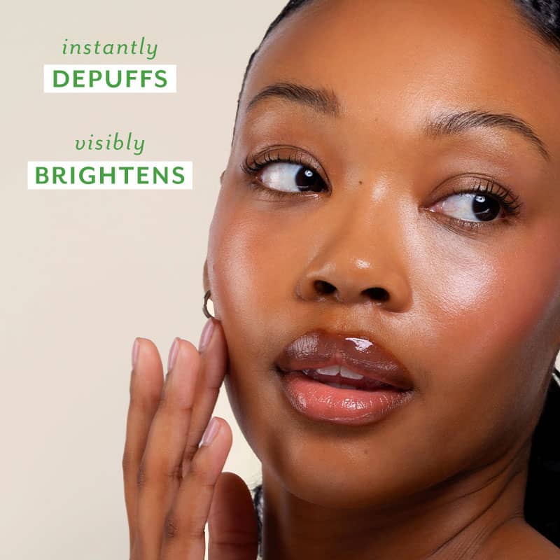Woman applying skincare product with text 'instantly DEPUFFS visibly BRIGHTENS' on a beige background