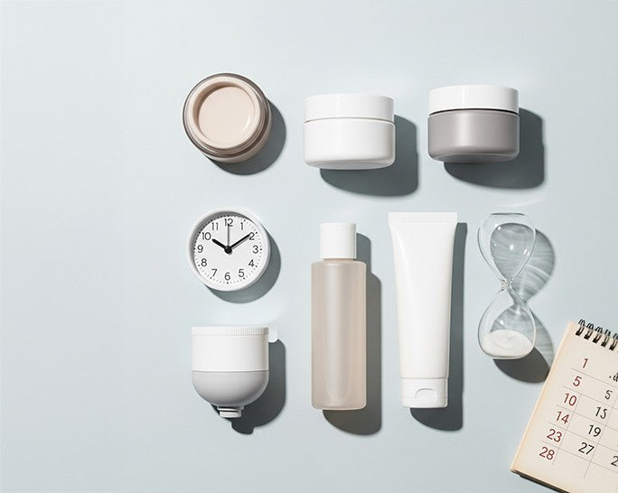 skin products laying on a blue background with a clock and calendar