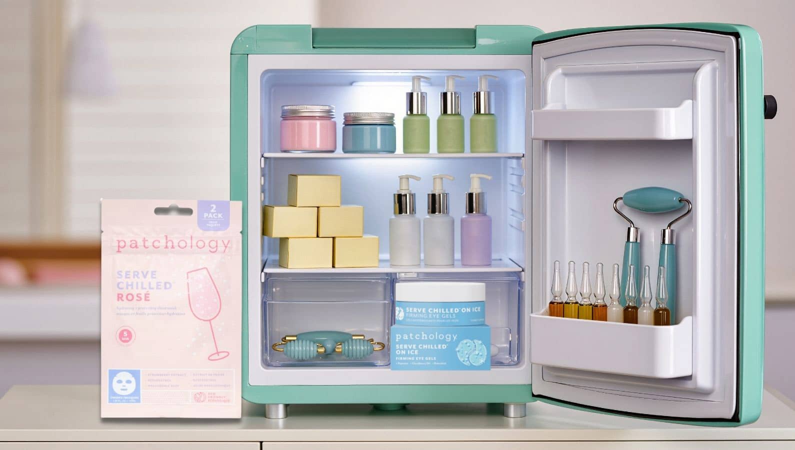 Mini skincare fridge stocked with Patchology products, serums, and tools, alongside Serve Chilled Rosé sheet masks, highlighting a cooling, spa-like beauty routine at home.